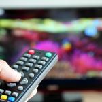 Hand pointing a tv remote control towards the television